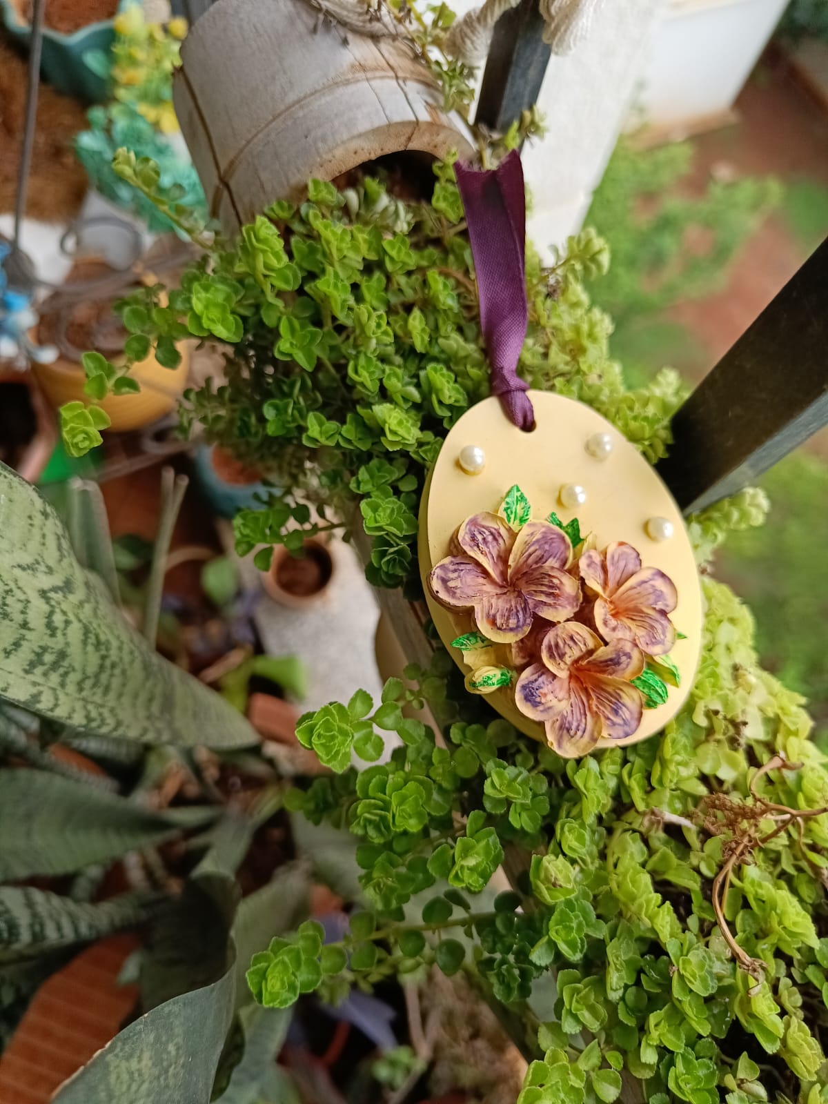 Yellow egg-shaped hanging aroma stone with purple flowers in a garden