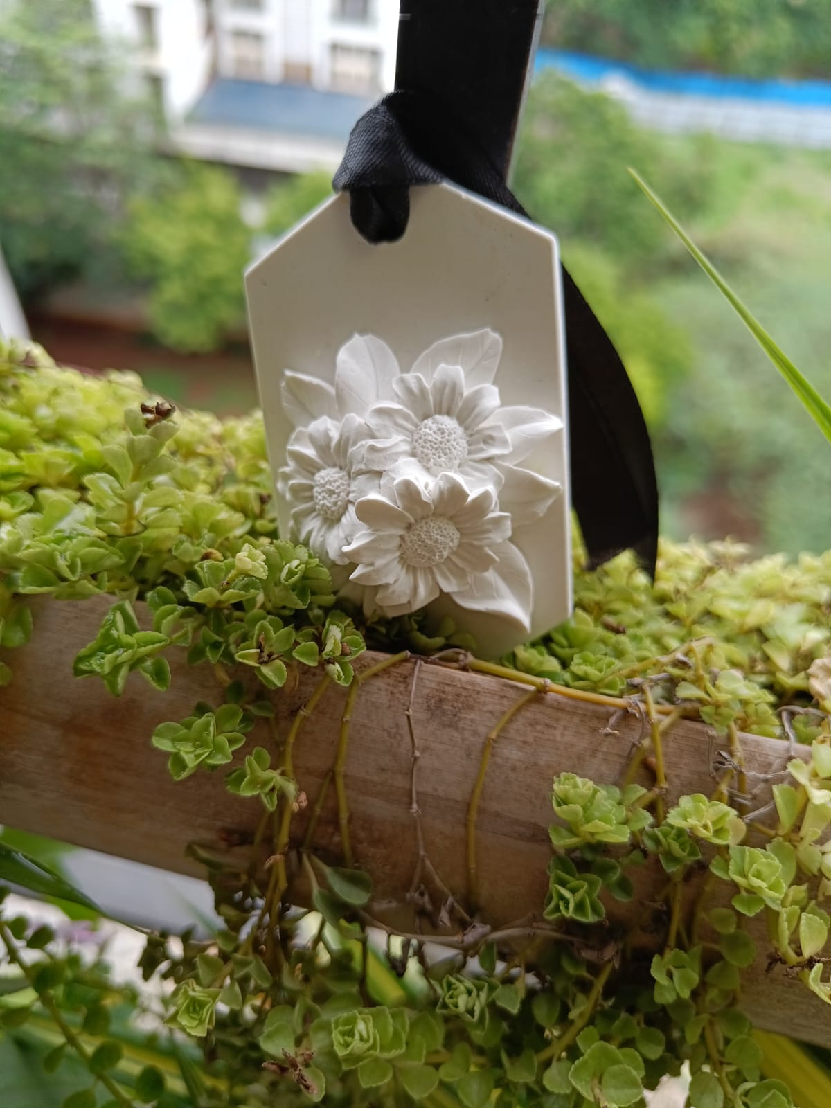White floral hanging aroma stone tag with a black ribbon