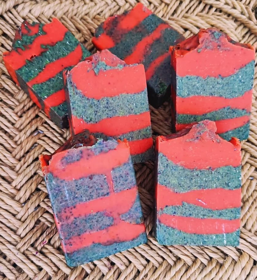Red and green watermelon-style striped cold process soap bars on a woven basket, from the 24-Hr Faster Curing Cold Process Soap Workshop